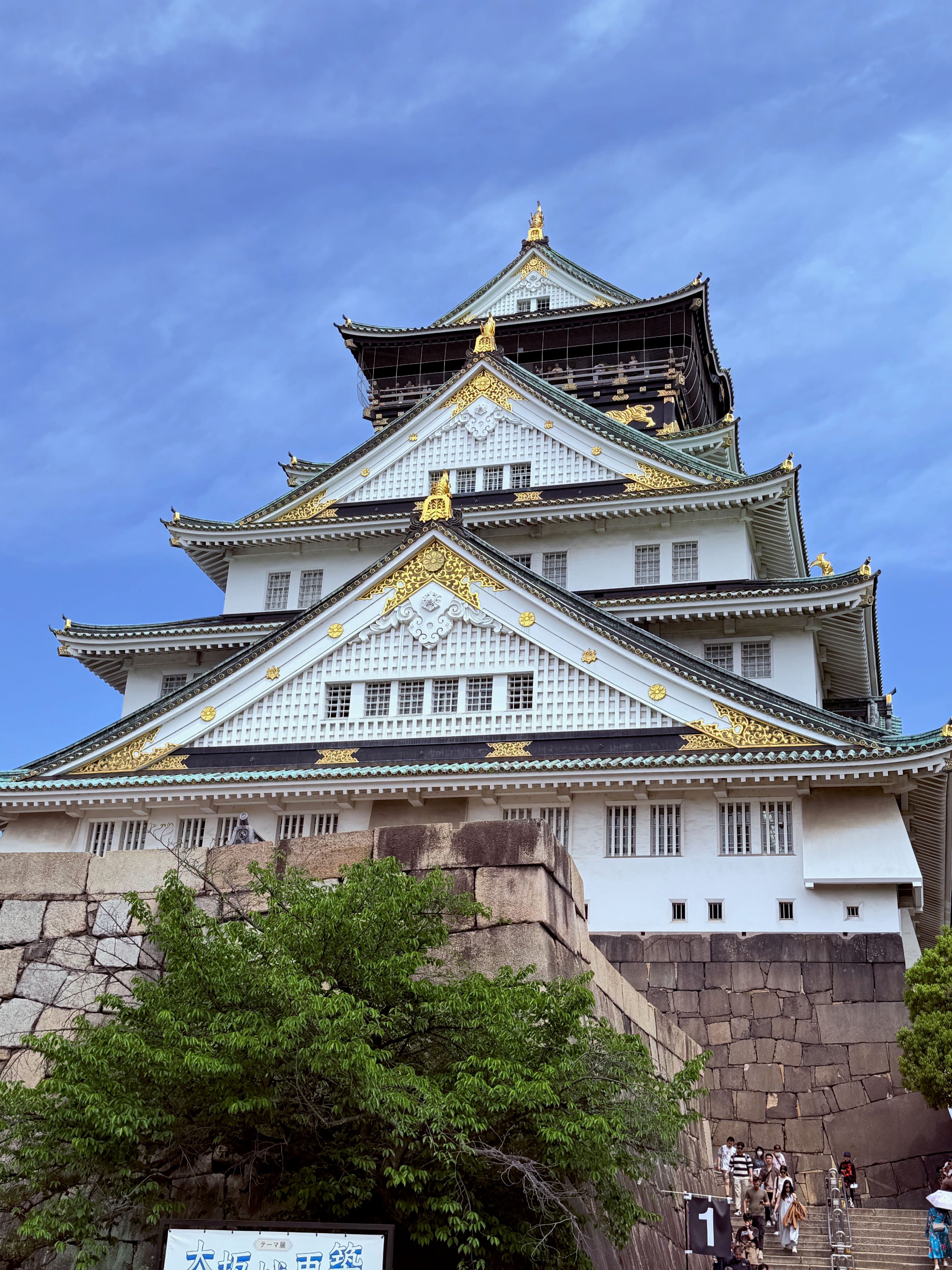 Osaka Castle tower rising above stone walls and green trees, Osaka Japan