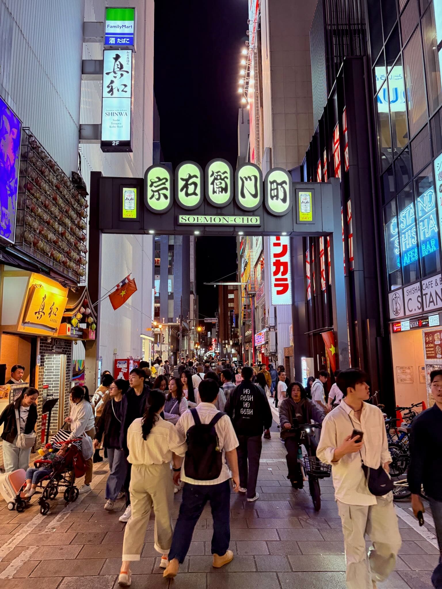 Glowing lanterns and neon signs lining a narrow street in Osaka at night, Japan