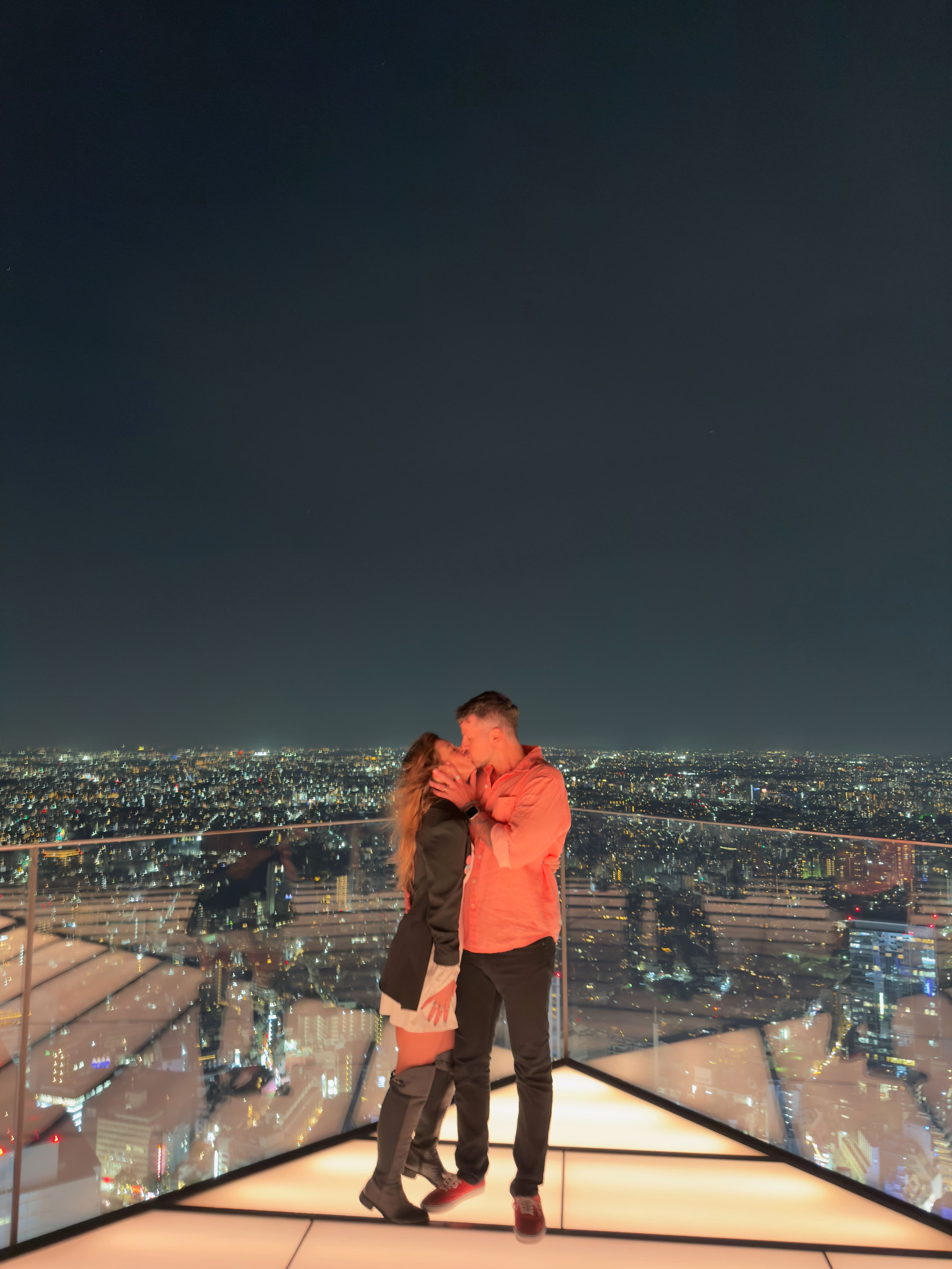 Open-air rooftop observation deck at Shibuya Sky with visitors looking over Tokyo at dusk, Japan