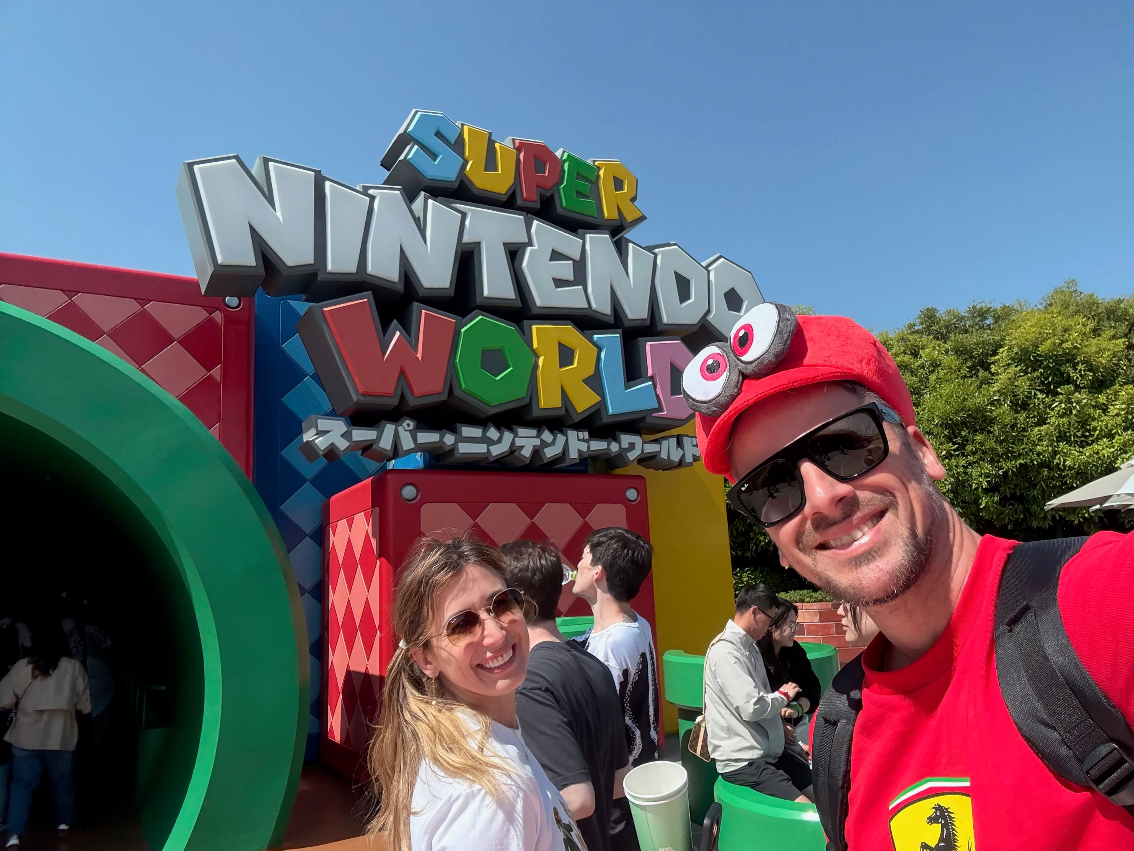 Inside Super Nintendo World at USJ with the Mushroom Kingdom landscape, Question Blocks and visitors wearing Mario caps, Japan